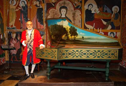 Roberto de Regina com roupa de época apoiado em um cravo.