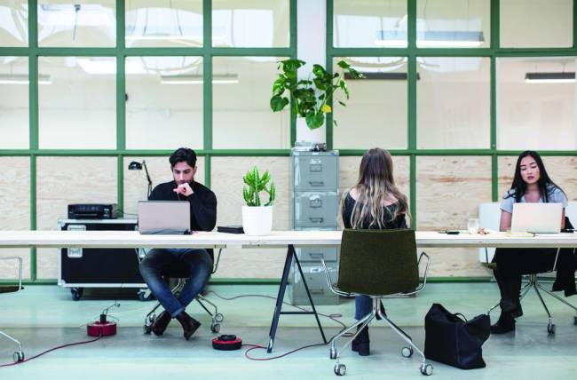 Two women and one man working at desk in creative office