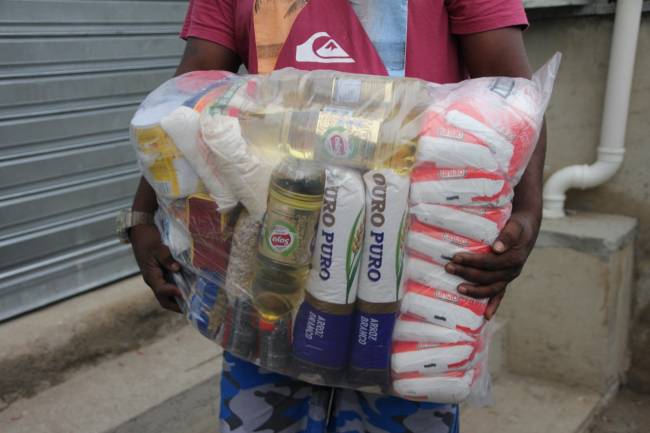Distribuição de cestas da campanha Maré diz não ao coronavírus – Foto de Kamila Camillo Homem carrega alimentos como arroz, óleo e feijão