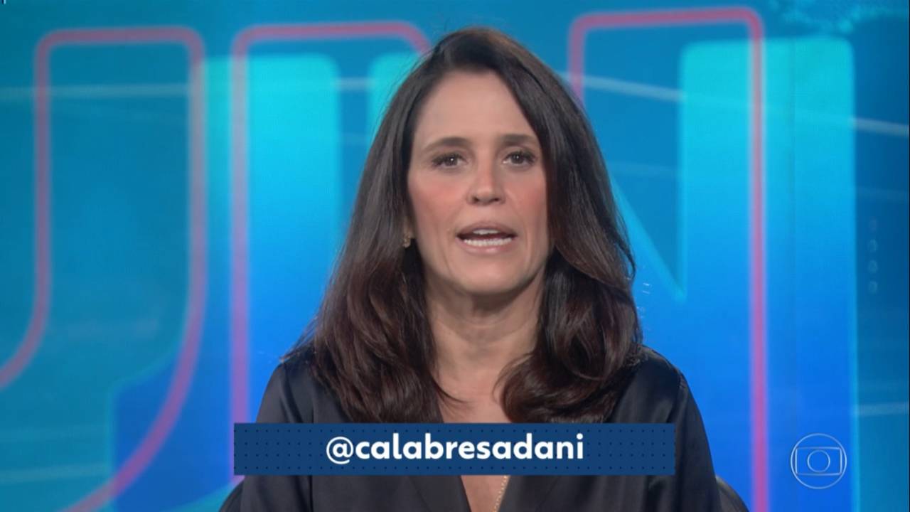 A imagem mostra a apresentadora Ana Luiza Guimarães na bancada do Jornal Nacional