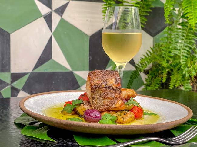 A imagem mostra um lombo de bacalhau com taça de vinho branco