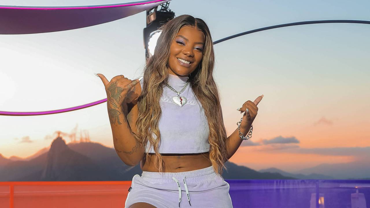 A imagem mostra a cantora Ludmilla sorrindo e fazendo sinal de positivo com as mãos