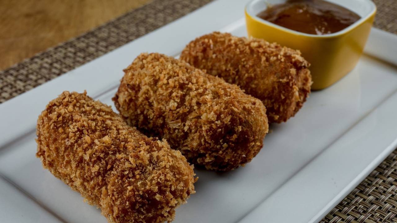 A imagem mostra bolinhos fritos acompanhados de molho