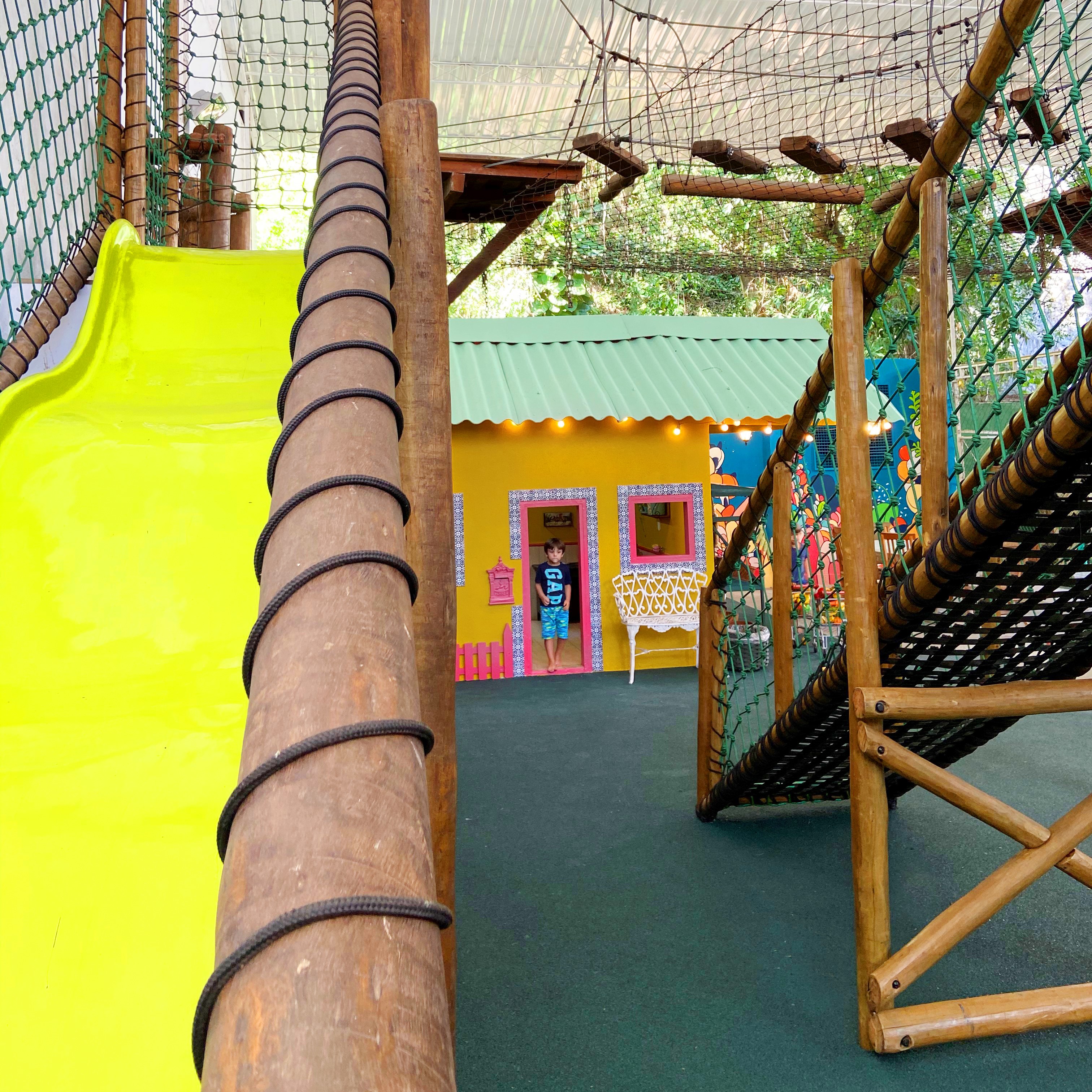 Casa de festas com brinqued&atilde;o e crian&ccedil;a brincando ao fundo