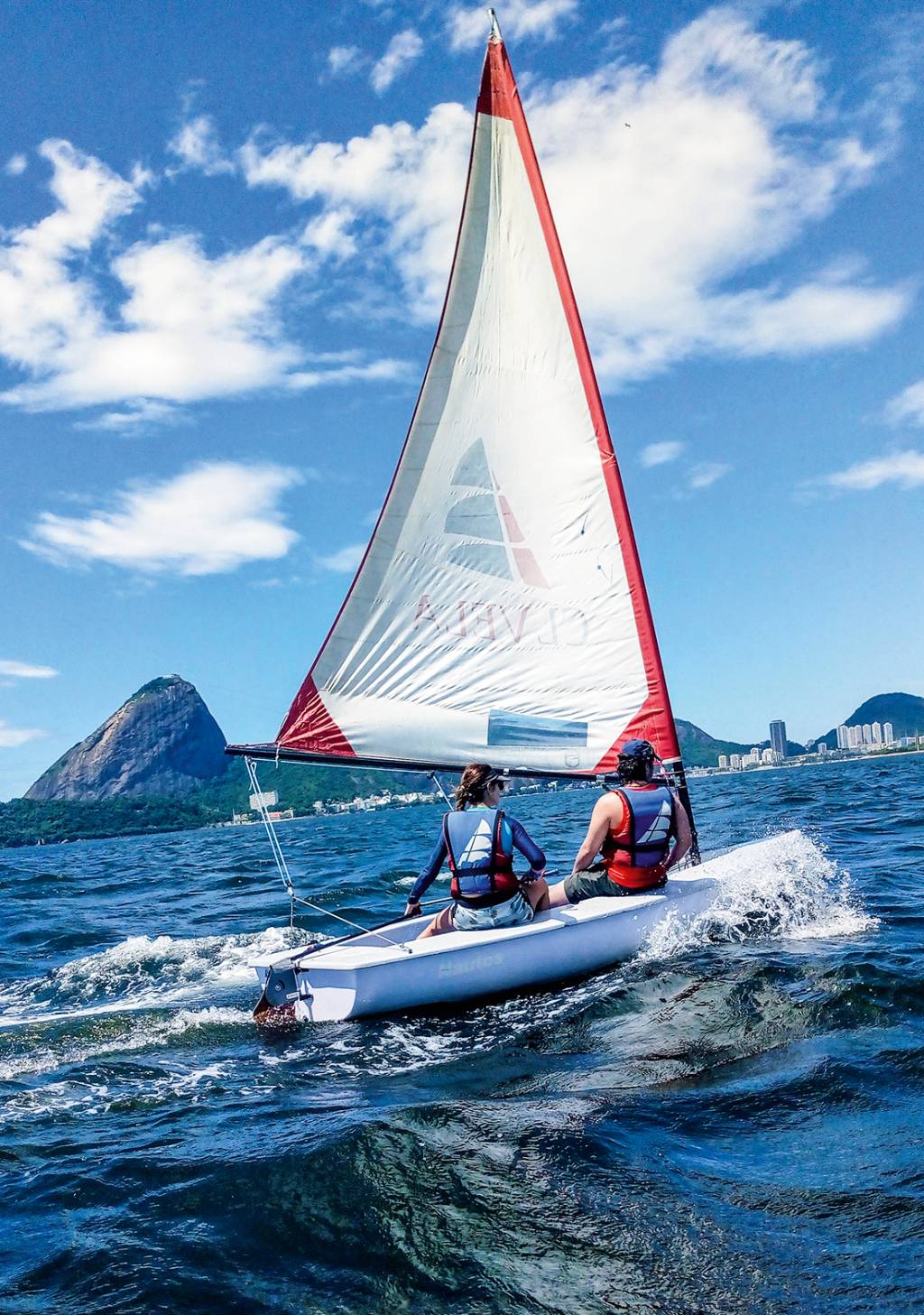 aula_dingue_2.jpg A imagem mostra duas pessoa num dingue, barco a vela, nas águas da Baía de Guanabara