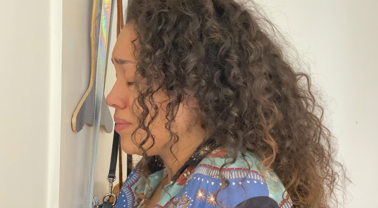 Menina de perfil, cabelos encaracolados, chorando