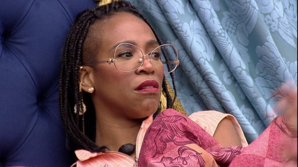 Mulher negra com tranças usando óculos faz cara de desgosto