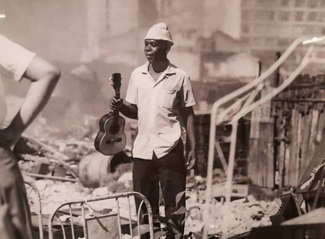 Morador resgata seu cavaquinho depois do incêndio no Morro do Pinto, até hoje investigado como criminoso. A destruição pelo fogo deixou centenas de desabrigados nos anos 1960 e possibilitou a construção do condomínio Selva de Pedra, no Leblon. Reprodução de Alexandre Gomes