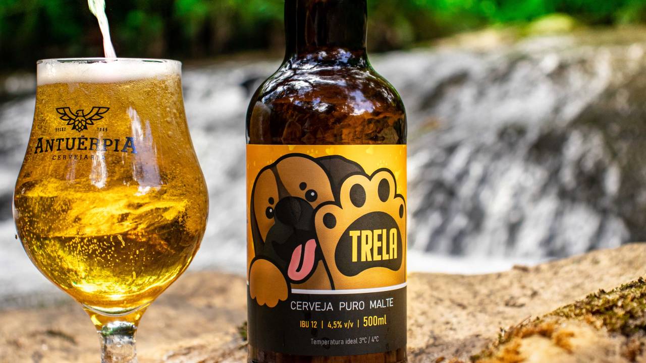 Garrafa de cerveja Trela pilsen com taça cheia ao lado