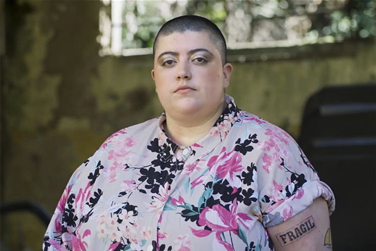 A imagem mostra a cantora Ana Vilela vestida com camisa estampada