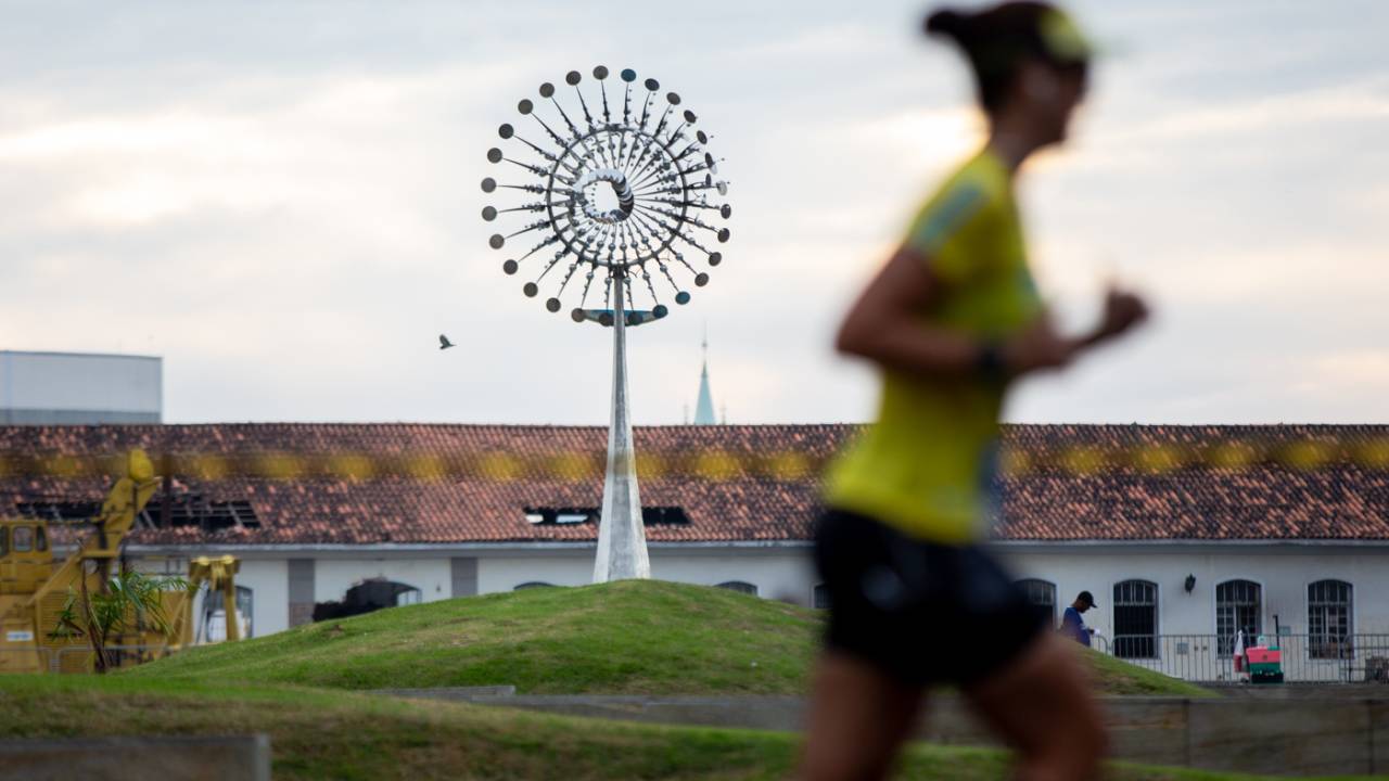 Corredora passa em frente à Pira Olímpica
