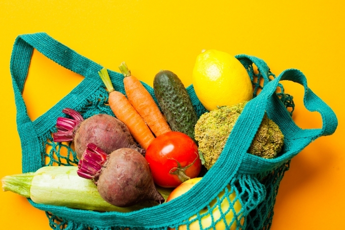 Sacola de pano furadinha com frutas e vegetais dentro