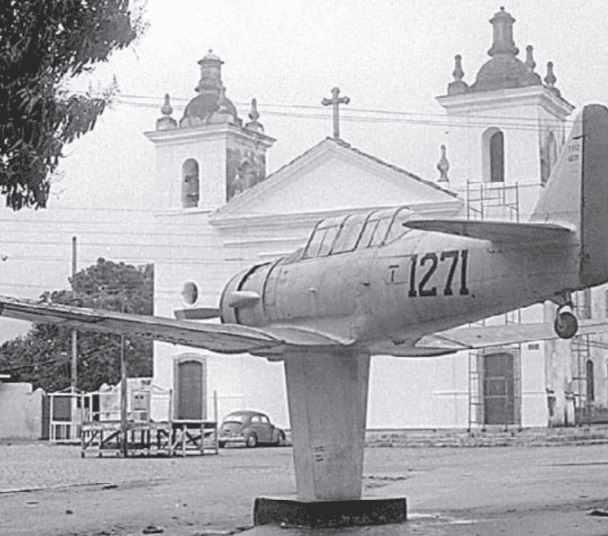 Foto do monumento de uma avião na frente da Igreja de Nossa Senhora do Loreto (1974)