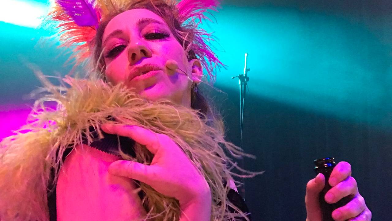 Uma mulher como cocar de penas em uma iluminação rosa