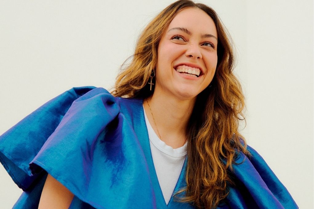 Cantora manda sorri com uma blusa azul de enormes mangas
