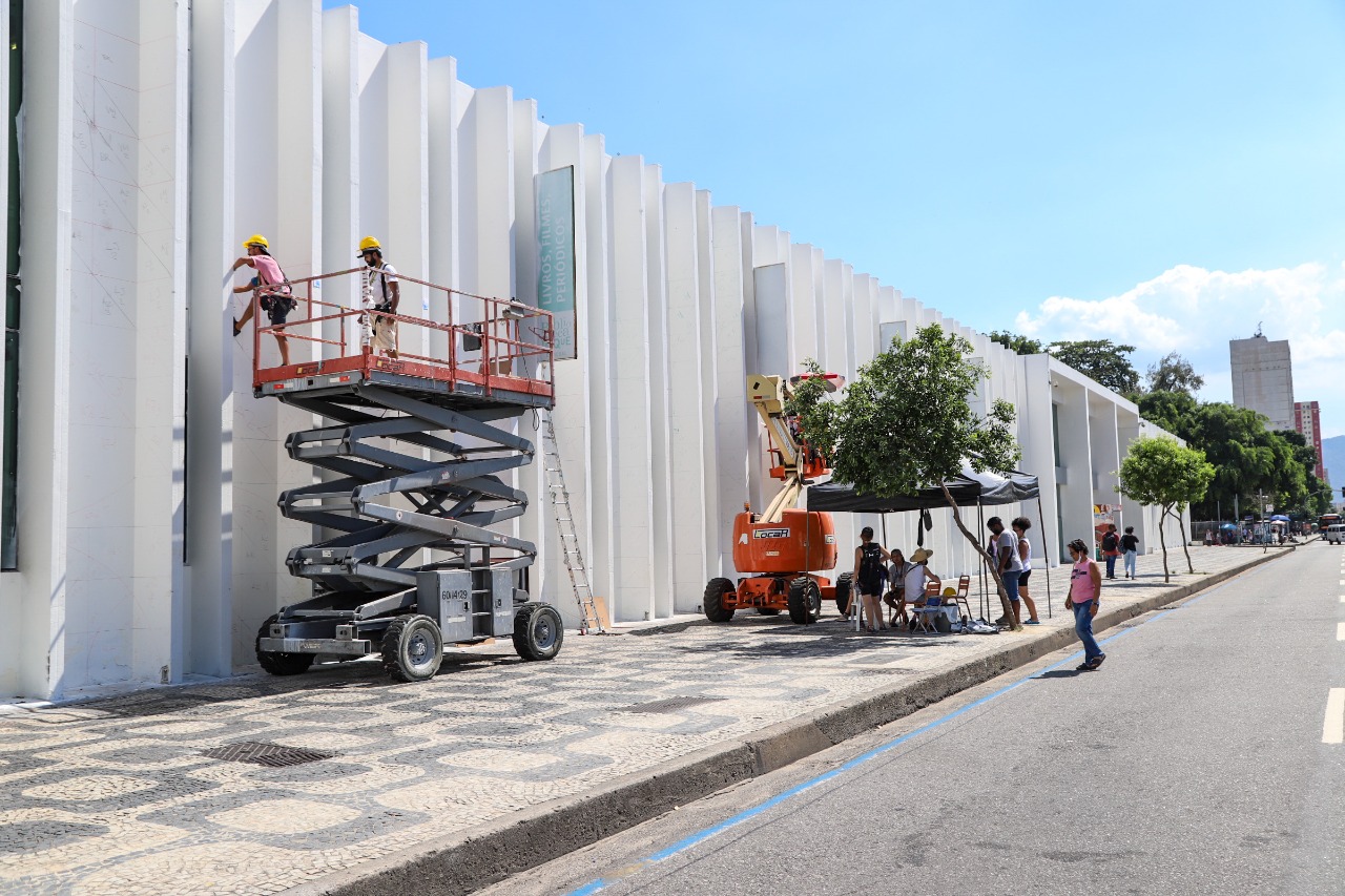 Foto mostra fachada da biblioteca parque sendo pintada