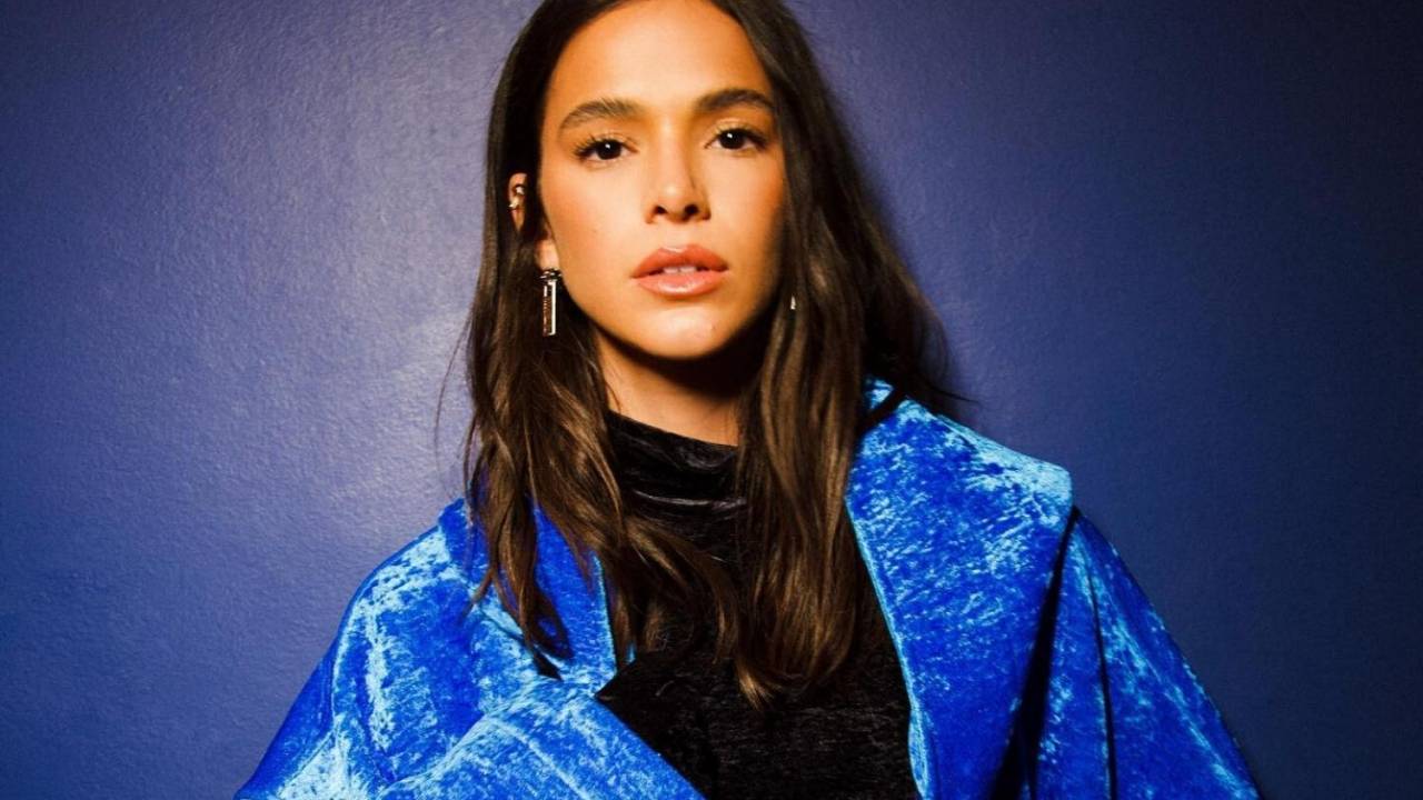 Foto mostra a atriz Bruna Marquezine usando roupa preta com casaco azul