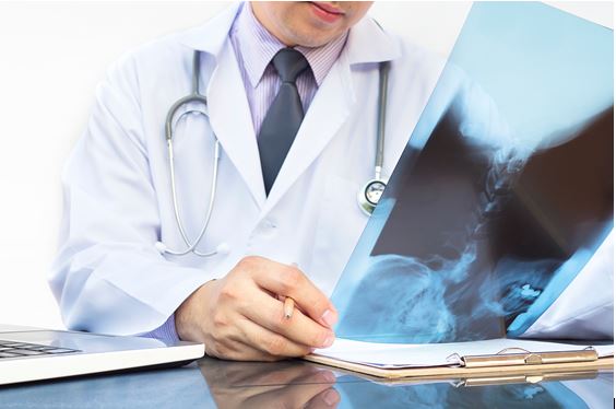 Médico analisa exame de raio X.