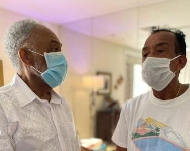 À esquerda, Gilberto Gil de camisa branca e máscara descartável azul-claro. À direita, Jorge Ben Jor de camiseta branca com estampa da grife Casablanca e máscara descartável branca.