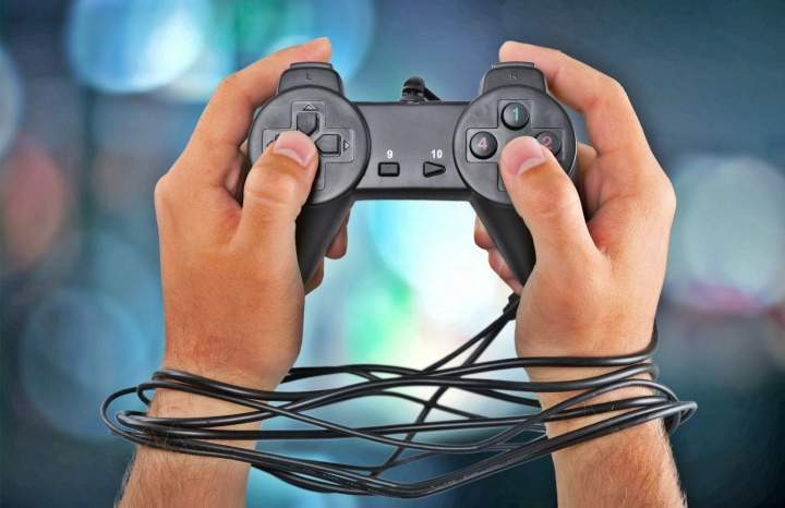 Uma pessoa segura um joystick com as mãos amarradas por fios.