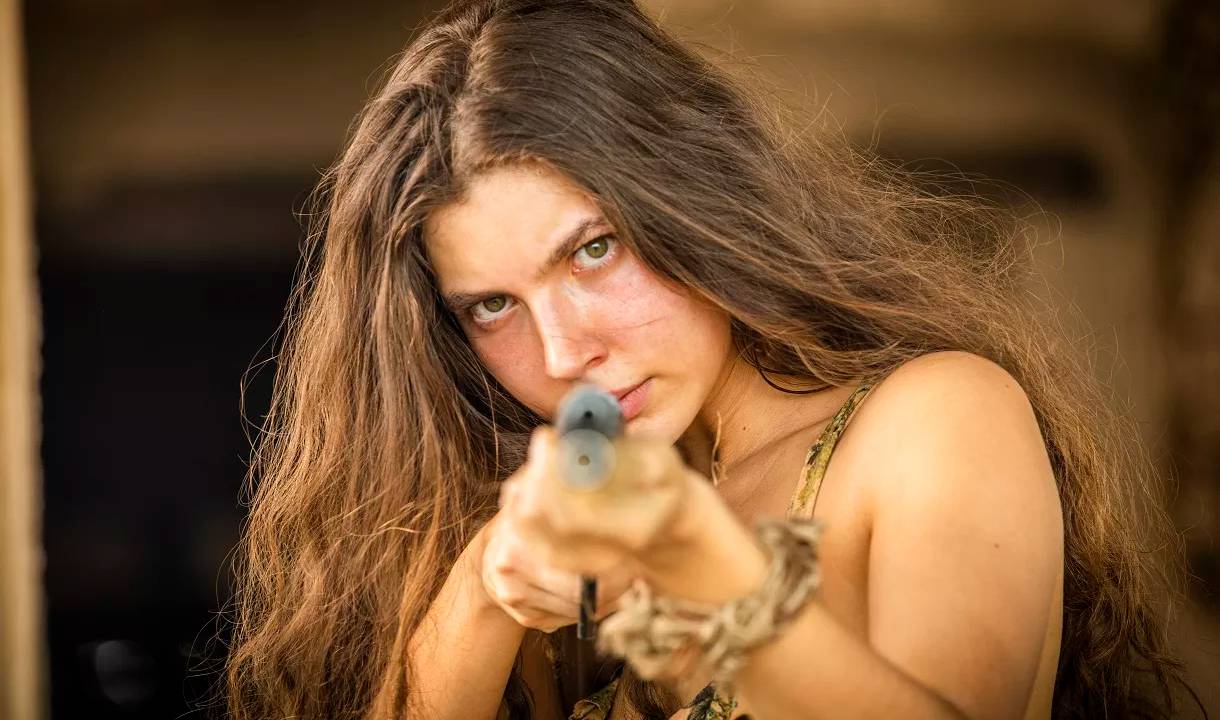 Alanis Guillen empunha uma espingarda, na pele da personagem Juma, de Pantanal.