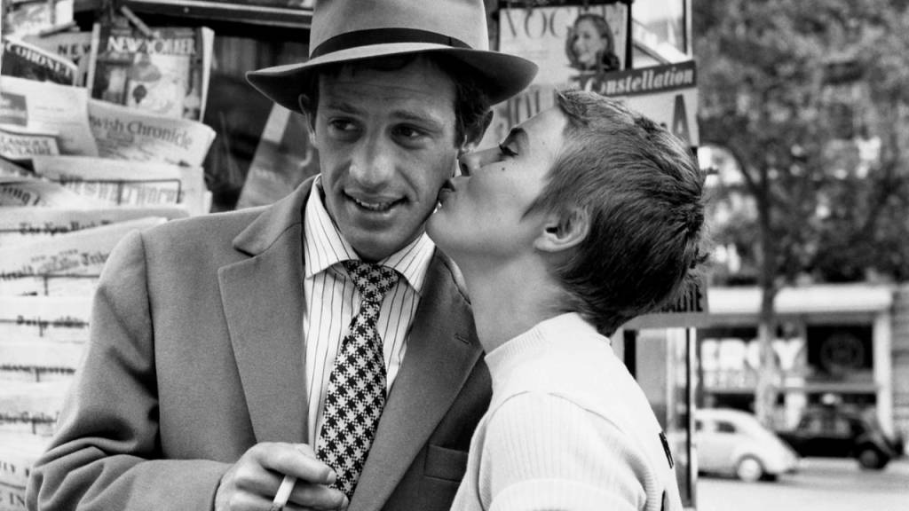 image-w1280 Foto mostra cena de filme de Godard em que mulher dá beijo na bochecha de um homem usando chapéu e terno, segurando um cigarro na mão