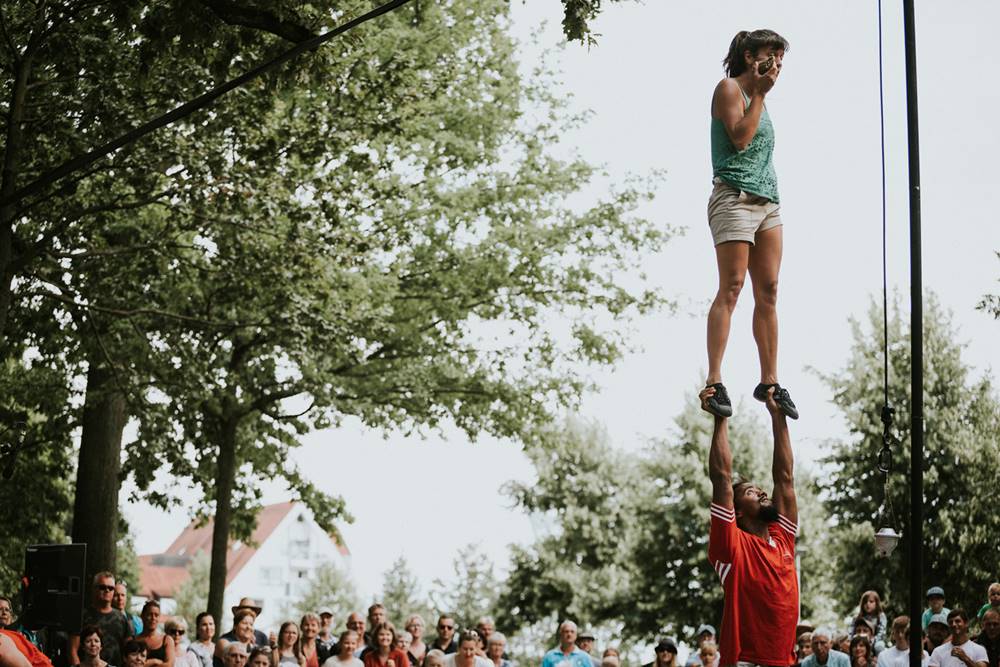 CiaDelaPraka – Foto_TOMÁŠ HUDOLIN 9 Uma mulher está de pé sobre as mãos de um homem em uma apresentação de acrobacia.