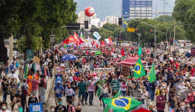 Passeata pela democracia com centennas de pessoas carregando faixas e bandeiras