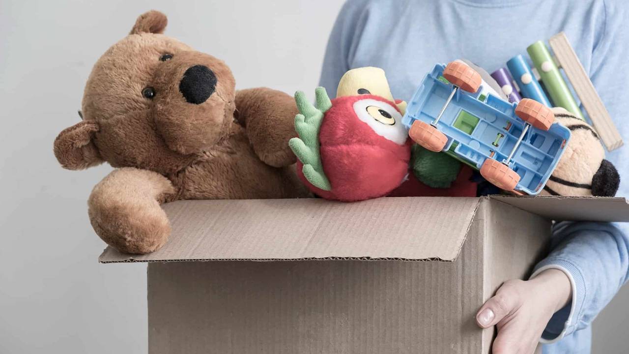 Foto mostra menino com caixa de brinquedos