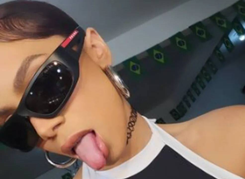 Anitta de óculos escuros, cabelo preto e top preto com as bordas brancas.