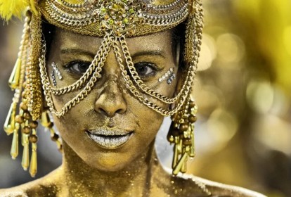 Foto mostra foto de mulher com rosto e acessórios de carnaval dourados