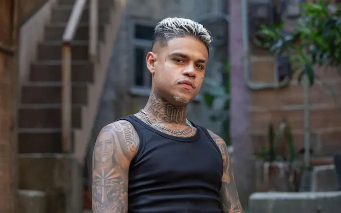 MC Cabelinho com o cabelo descolorido. Ele usa camiseta preta sem manga.