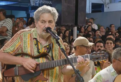 Foto mostra Moacyr Luz tocando e cantando em roda de samba