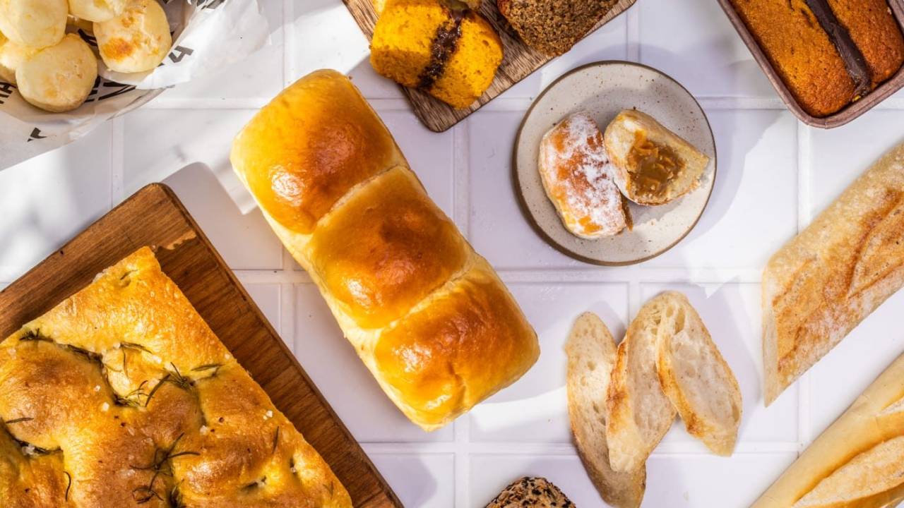 Mesa com vários tipos de pão e bolos fotografada de cima