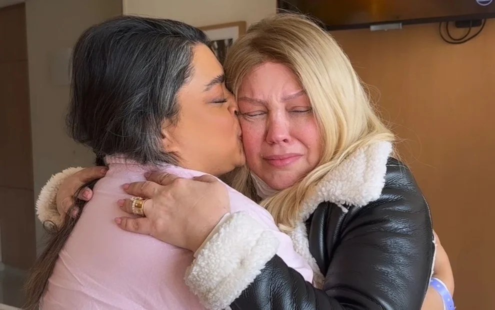 Foto mostra as cantoras Preta Gil e Simony se abraçando. Preta dá um beijo na bochecha da outra cantora