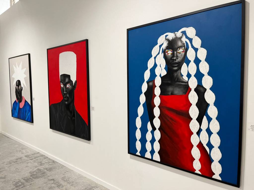 Igor Rodrigues À esquerda, uma tela quadrada de um homem negro com corte de cabelo flat top branco, sobre fundo vermelho. à direita, uma mulher negra de vestido vermelho, com cabelo com tranças.