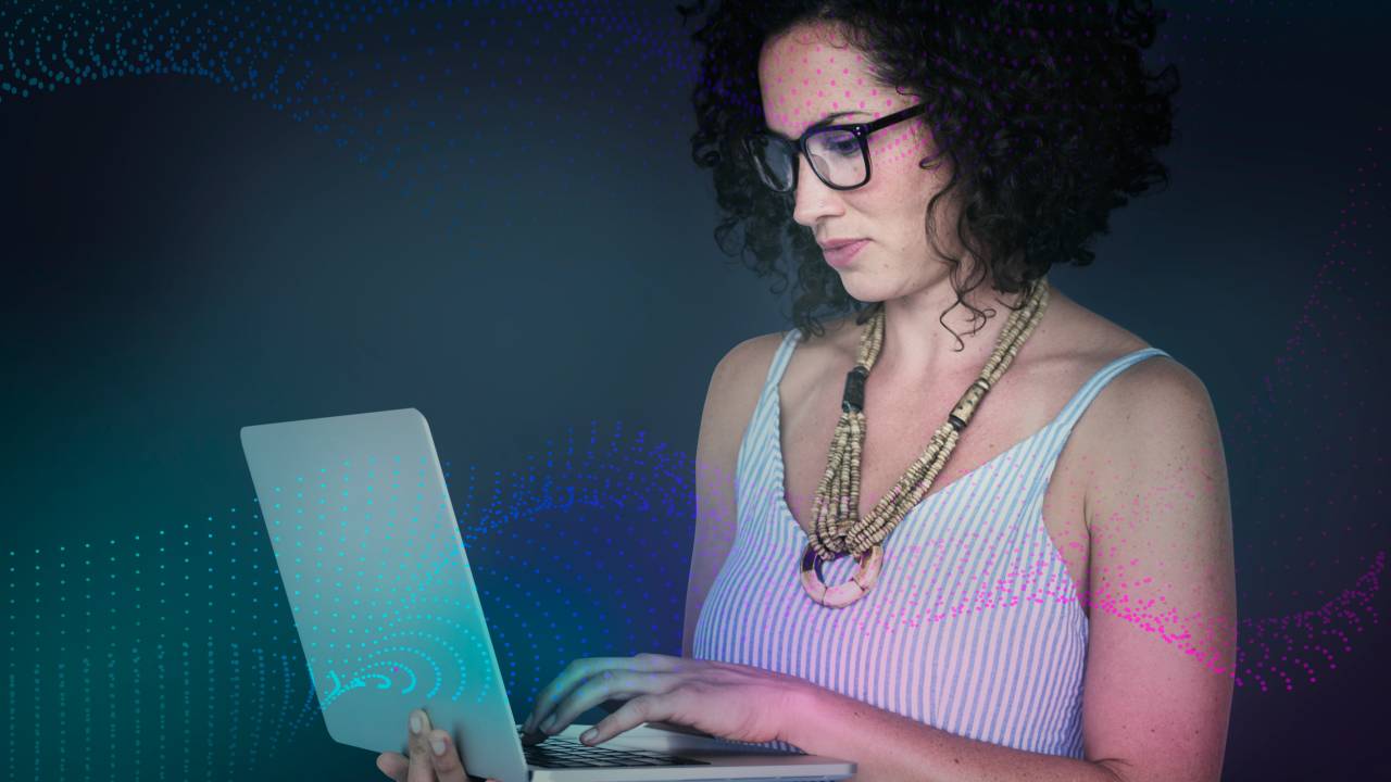 Mulher segura um laptop enquanto olha pra tela.