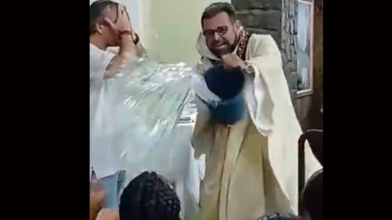 Padre João Cláudio, da igreja de Nossa Senhora de Fátima, em Niterói, dá uma "baldada" de água benta nos integrantes da Viradouro